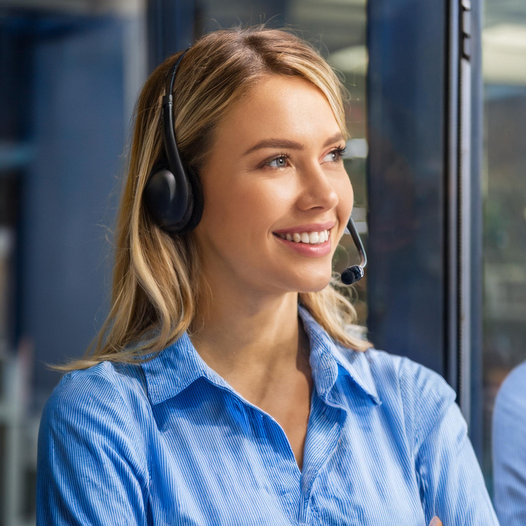 Eine freundlicher Mitarbeiter eines Callcenters trägt was blaues und schaut nach rechts