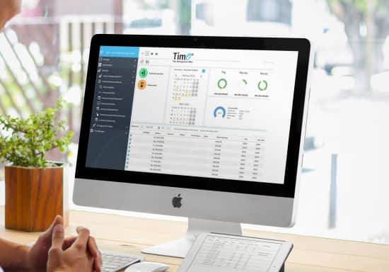 Arbeitsplatz mit Computerbildschirm, der eine Zeiterfassungssoftware mit Kalender und Statistiken anzeigt.