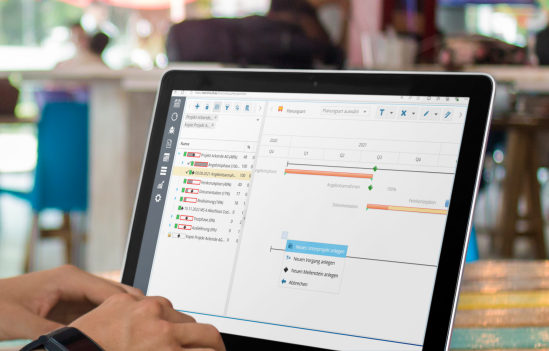 Ein Nutzer arbeitet an einem Laptop mit einer Projektmanagement-Software, die ein Gantt-Diagramm zur Projektplanung zeigt.
