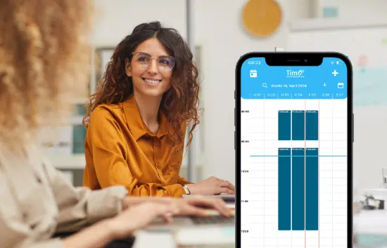 Smartphone mit geöffneter Dienstplan-App vor einem Bürogespräch, das eine übersichtliche Schichtplanung für den Tag anzeigt.