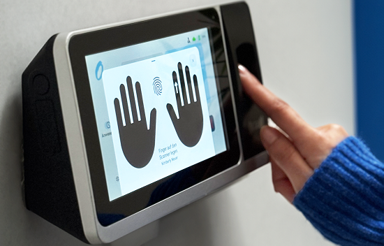 Wandmontiertes Zeiterfassungsterminal mit Fingerabdrucksensor wird von einer Person benutzt.