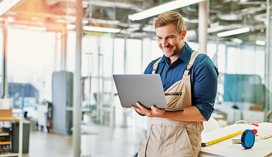 Ein Handwerker nutzt Rechnungssoftware mobil am Laptop in der Werkstatt.