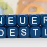 Aufgereihte Buchstabenwürfel vor Geldscheinen zeigen den Hinweis auf den neuen mindestlohn 2026