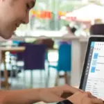 „Mitarbeiter nutzt eine digitale Zeiterfassung auf einem Laptop zur Erfassung von Arbeitszeiten im Büro.“