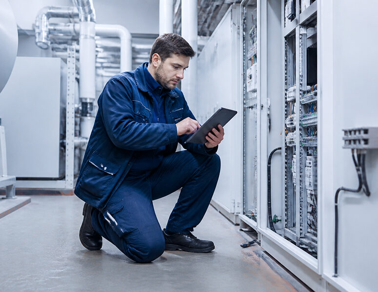 Techniker nutzt ein Tablet zur digitalen Leistungserfassung an einer elektrischen Anlage.