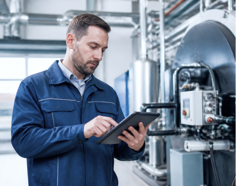 Servicetechniker nutzt ein Tablet an einer Industrieanlage zur digitalen Dokumentation seiner Arbeiten.